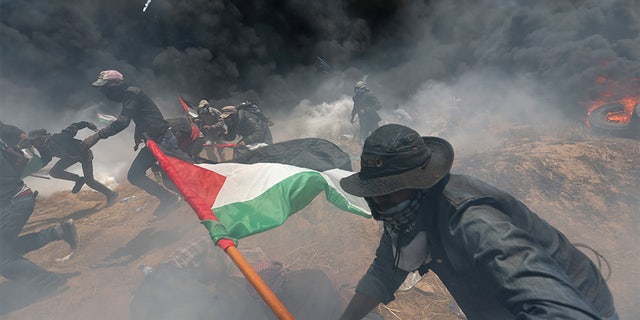 May 14, 2018: Palestinian demonstrators run for cover from Israeli fire and tear gas during a protest against the U.S. embassy move to Jerusalem.