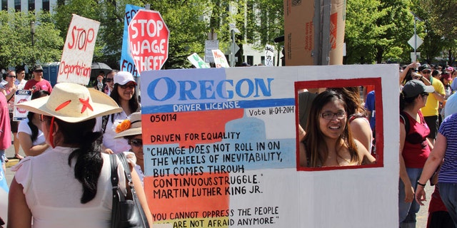 FILE - In this May 1, 2014 file photo, Nathalie Marquez holds a sign modeled after an Oregon drivers license at the Capitol, in Salem, Ore. As President Obama moves toward taking action to allow millions of people in the country illegally to stay and possibly work, the outcome of a little-noticed ballot measure in deep-blue Oregon serves as a warning to him and his party on the volatility of the immigration issue. (AP Photo/Chad Garland, file)