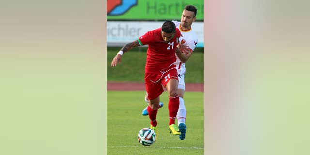 Iran's Ashkan Dejagah, left, challenges for a ball with Marko Vesovic, right, of Montenegro during a friendly soccer match between Iran and Montenegro, in Hartberg, Austria, Monday, May 26, 2014. (AP Photo/Ronald Zak)