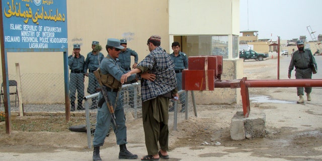 March 26, 2012: An Afghan policeman checks a man entering the provincial police station near the main gate of a joint civilian-military base where two British soldiers part of the NATO forces were killed in Lashkar Gah, Helmand province, south of Kabul, Afghanistan.