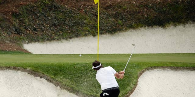 Phil Mickelson hits out of a bunker on the 12th hole during the second round of the Masters golf tournament Friday, April 11, 2014, in Augusta, Ga. (AP Photo/Charlie Riedel)