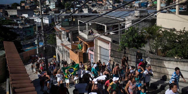 Residents take part in a protest march calling attention to the violence that erupts during police operations against suspected drug traffickers, in the Alemao slum complex in Rio de Janeiro, Brazil, Friday, April 3, 2015. Residents are protesting the shooting deaths of a young boy and a 41-year-old housewife, who were killed by stray bullets in the past few days. (AP Photo/Felipe Dana)