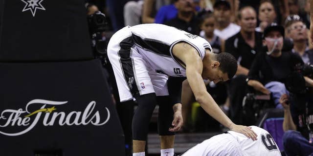 San Antonio Spurs forward Tim Duncan, left, checks on guard Tony Parker during the second half in Game 2 of the NBA basketball finals against the Miami Heat on Sunday, June 8, 2014, in San Antonio. Miami won 98-96. (AP Photo/Eric Gay)