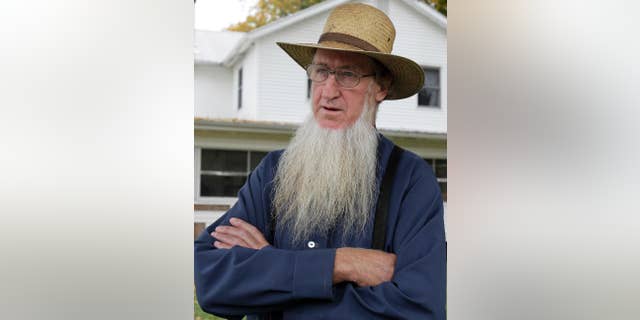 FILE - In this Oct. 10, 2011 file photo, Sam Mullet Sr. stands in the front yard of his home in Bergholz, Ohio. Sixteen members of a breakaway Amish community from eastern Ohio are scheduled to be resentenced in Cleveland after a federal appellate court overturned their hate crime convictions. The resentencing Monday, March, 2, 2015, is needed because the original sentences for the 16 didn’t distinguish between their hate crimes convictions and convictions on other charges related to the forced cutting of beards and hair of seven people. All were members of other Ohio Amish communities. Eight of the 16 already have served their sentences and can’t be returned to prison. (AP Photo/Amy Sancetta, File)