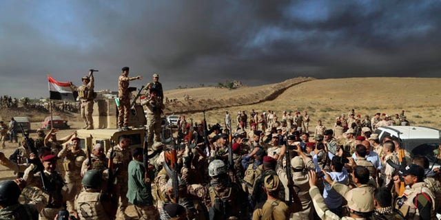 OCT. 21: Iraqi Army soldiers raise their weapons in celebration on the outskirts of Mosul, Iraq