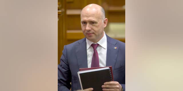 File - In this Wednesday, Jan. 20, 2016, file picture, Moldovan Premier, Pavel Filip, walks after delivering a speech in parliament before his pro-European government was approved in Chisinau, Moldova. Wednesday, Jan. 20, 2016. Premier Pavel Filip, who became the sixth prime minister of this impoverished former Soviet republic in January 2016, told The Associated Press on Wednesday April 27, 2016, that badly needed reforms in Moldova must start with the government.(AP Photo/Roveliu Buga, FILE)