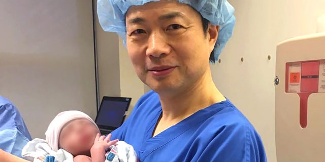 In this undated image, Dr. John Zhang holds a baby believed to be the first-ever born using DNA from three people