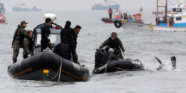 South Korean navy's frogman dives into a water to search passengers believed to have been trapped in the sunken ferry Sewol in the water off the southern coast near Jindo, south of Seoul, South Korea, Saturday, April 19, 2014. The captain of the sunken South Korean ferry was arrested Saturday on suspicion of negligence and abandoning people in need, as investigators looked into whether his evacuation order came too late to save lives. Two crew members were also arrested, a prosecutor said. (AP Photo/Lee Jin-man)