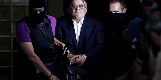 The leader of Greece's Golden Dawn party Nikos Michaloliakos is escorted by masked police officers in Athens, on September 28, 2013