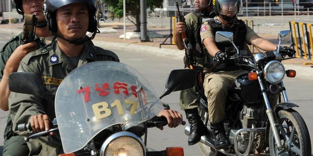 Cambodian police officials ride their motorbikes in Phnom Penh on March 21, 2012