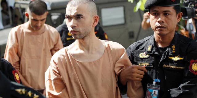 FILE - In this Nov. 24, 2015 file photo, police officers escort suspects in the Aug. 17 blast at Erawan Shrine, Bilal Mohammad, front, and Mieraili Yusufu, rear, as they arrive at a military court in Bangkok, Thailand. Testimony begun Tuesday, Nov. 15, 2016 in the trial of two men accused of the deadly 2015 bombing at a Bangkok landmark after a dispute over the defendants' translators. (AP Photo/Sakchai Lalit, File)
