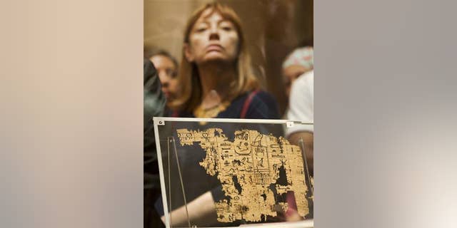 A visitor looks at one of the oldest papyri in the history of Egyptian writing among the collection of King Khufu papyri discovered at Wadi El-Jarf port, as it is on display for the first time at the Egyptian museum in Cairo, Egypt, Thursday, July 14, 2016.