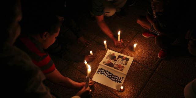 South Africans light candles during a vigil held in Johannesburg Wednesday, Jan. 18, 2017, for South African freelance photographer Shiraaz Mohamed who was abducted in Syria last week. People prayed and held signs calling for the safe return of Mohamed who was kidnapped on Jan. 10, while traveling with aid workers to Syria's border with Turkey. (AP Photo/Denis Farrell)