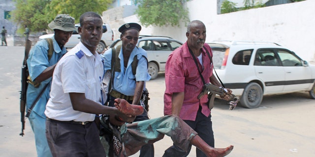 Somali soldiers carry a wounded civilian from the entrance of Mogadishus court complex after being injured during a siege by militants, in Mogadishu, Somalia, Sunday, April 14, 2013. (AP)