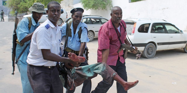 Somali soldiers carry a wounded civilian from the entrance of Mogadishus court complex after being injured during a siege by militants, in Mogadishu, Somalia, Sunday, April 14, 2013. (AP)