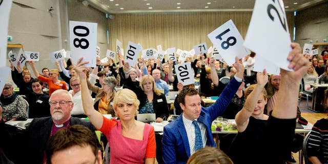 Norwegian Church Council leader Kristin Gunleiksrud Raaum, centre, in red, and Chairman of the Oslo diocesan council Gard Sandaker-Nielsen, centre, right, vote to allow homosexuals to be married within the Norwegian Church. The Church of Norway voted on Monday April 11, 2016 in Trondheim, Norway to approve new marriage ceremony rules that will allow homosexuals to be married within the church. (Ole Martin Wold / NTB scanpix via AP) NORWAY OUT