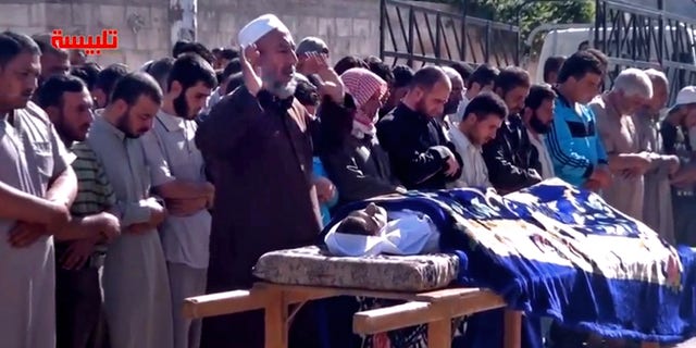 In this image taken from video obtained from the Shaam News Network, which has been authenticated based on its contents and other AP reporting, Syrians participate in the funeral prayer for Youssef Ghazi al-Sarmani who was killed in fighting between rebel and government forces, Monday, May 27, 2013. Logo in red reads, "Talbiseh". (AP Photo/Shaam News Network via AP video)