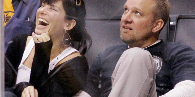 **FILE** Actress Sandra Bullock laughs as she watches the video board with her husband Jesse James during the Los Angeles Kings' NHL hockey game against the Anaheim Ducks, in this Oct. 22, 2006 file photo in Los Angeles. Before she got to know him, Bullock says she tagged her husband as a brutish "bigot." (AP Photo/Mark J. Terrill, file)