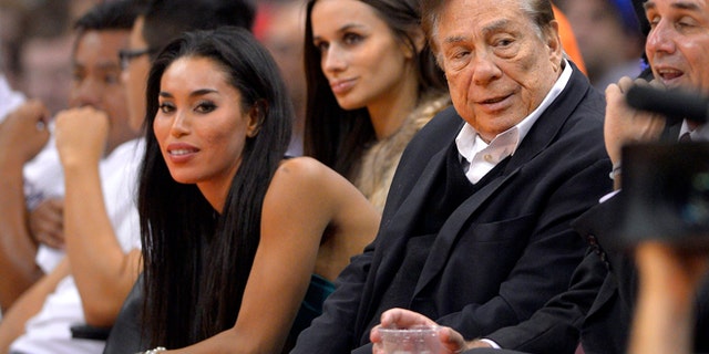 Los Angeles Clippers owner Donald Sterling, right, and V. Stiviano, left, watch the Clippers play the Sacramento Kings. (AP)