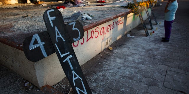 FILE - In this Oct. 28, 2014, file photo, a local resident pauses to contemplate crosses set to remember 43 missing students, in front of the burnt town hall, in Iguala, Mexico. Argentine forensics experts on Saturday Feb. 7, 2015, questioned Mexicoâs investigation into the disappearance of 43 students, saying the evidence doesnât support the governmentâs conclusion the youths were killed and burned to ashes. (AP Photo/Rebecca Blackwell, File)