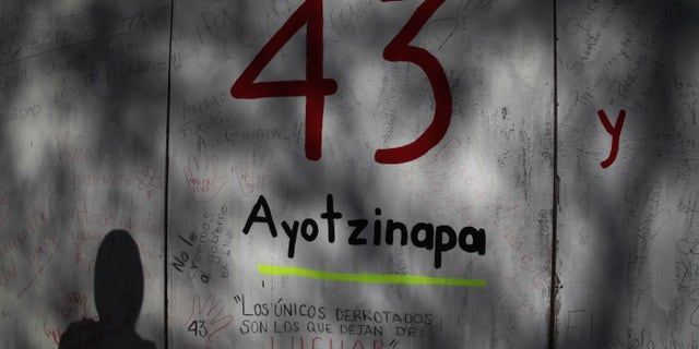 FILE - In this Dec. 28, 2014 file photo, the shadow of a demonstrator is cast on a wall with graffiti protesting the disappearance of 43 rural college students, in front of the Mexican Attorney General's office, in Mexico City. Mexican prosecutors said Tuesday, Jan. 20, 2015, that an Austrian forensics lab has been unable to find any more DNA that could be used by conventional means to identify charred remains that might be those of missing college students, but said they have authorized a final, unconventional effort. (AP Photo/Marco Ugarte, File)