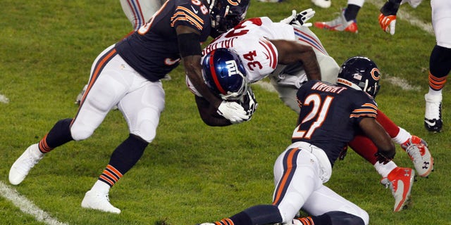 Chicago Bears linebacker D.J. Williams (58) and safety Major Wright (21) tackle New York Giants running back Brandon Jacobs (34) In the first half of an NFL football game, Thursday, Oct. 10, 2013, in Chicago. (AP Photo/Kiichiro Sato)