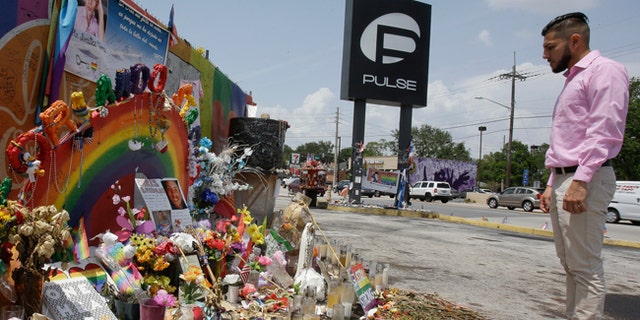 In this Tuesday, May 30, 2017 photo, Marco Quiroga, who works to support LGBTQ and social-justice causes in central Florida, reflects in front of one of the memorials at the Pulse Nightclub in Orlando, Fla. A year after the Pulse Nightclub shooting, the city's gay Latinos are trying to build up their community by forming support groups, seeking seats at the tables of power and creating a foundation to champion gays and Latinos. (AP Photo/John Raoux)