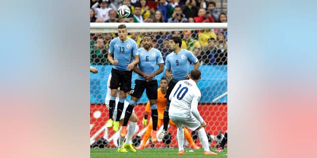 England's Wayne Rooney tries to get the ball over the Uruguay defensive wall on a free kick during the group D World Cup soccer match between Uruguay and England at the Itaquerao Stadium in Sao Paulo, Brazil, Thursday, June 19, 2014. (AP Photo/Kirsty Wigglesworth)