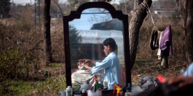 Roadside barber Adnan Khan shaves his customer in the suburbs of Islamabad, Pakistan on Tuesday, Feb. 12, 2013. Khan earns about Rs. 600 (US$6) a day to feed his family living in slum. (AP Photo/B.K. Bangash)