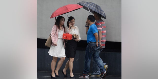 Filipinos use umbrellas as they go on their daily business at the financial district of Makati city east of Manila, Philippines under a slight rain Friday Oct. 11, 2013. A tropical storm barreling toward the northern Philippines on Friday intensified into a typhoon with destructive winds and flooding rains threatening farmlands and populated areas, including the capital Manila. Typhoon Nari forced U.S. Secretary of State John Kerry to call off Friday's trip to the Philippines. (AP Photo/Bullit Marquez)