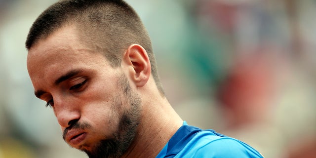 FILE - In this June 2, 2013, file photo, Serbia's Viktor Troicki blows out air as he plays France's Jo-Wilfried Tsonga during their fourth round match of the French Open tennis tournament at the Roland Garros stadium in Paris. Troicki’s doping ban was reduced from 18 months to 12 on Tuesday, Nov. 5, 2013 although he still cannot play in next week's Davis Cup final. (AP Photo/Christophe Ena, File)