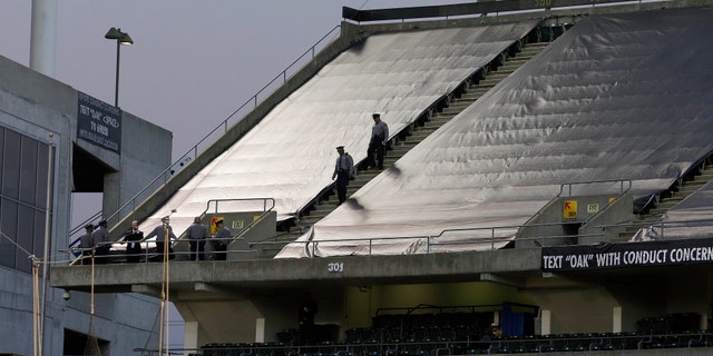 Law enforcement officials walk in the upper deck of O.co Coliseum after an NFL football game between the Oakland Raiders and the Tennessee Titans in Oakland, Calif., Sunday, Nov. 24, 2013. Authorities say a football fan jumped after the game from the third deck of the Oakland Coliseum, injuring herself and a man one level below who tried to catch her. She and the man who tried to catch her were rushed to the hospital for treatment. (AP Photo/Jeff Chiu)