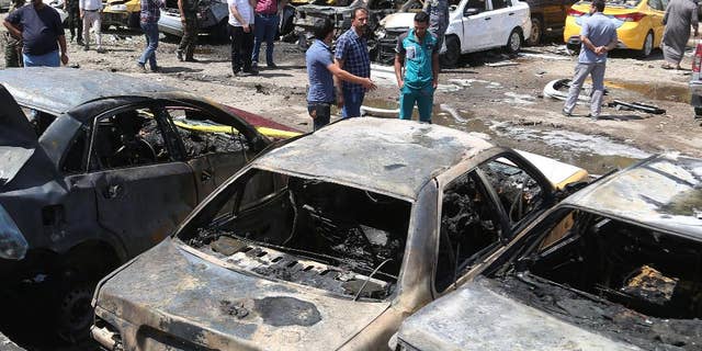 April 14, 2015: People and security forces gather at the scene of a car bomb explosion in a parking lot outside Yarmouk hospital in western Baghdad, Iraq. Car bombs went off Tuesday morning in and around the Iraqi capital, killing and wounding civilians, officials said.