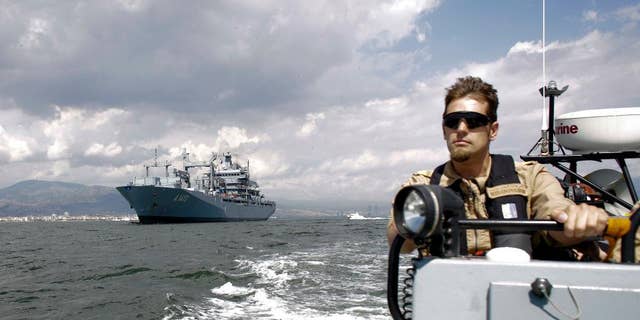 FILE - In this Thursday, May 26, 2016 file photo, The NATO German warship FGS Bonn, left, is escorted by a rescue boat as it departs from the harbor of the city of Izmir, Turkey. The FGS Bonn is part of the NATO flotilla patrolling the Aegean Sea in an effort to curb migrant activity between Turkey and Greece. (AP Photo/Markus Schreiber, File)