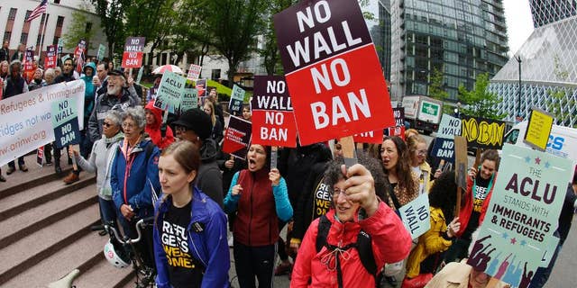Protesters wave signs and chant during a demonstration against President Donald Trump's revised travel ban, Monday, May 15, 2017, outside a federal courthouse in Seattle. A three-judge panel of the 9th U.S. Circuit Court of Appeals heard arguments Monday in Seattle over Hawaii's lawsuit challenging the travel ban, which would suspend the nation's refugee program and temporarily bar new visas for citizens of Iran, Libya, Somalia, Sudan, Syria and Yemen. (AP Photo/Ted S. Warren)