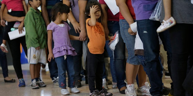 FILE - In this June 20, 2014, file photo, immigrants who entered the U.S. illegally stand in line for tickets at the bus station after they were released from a U.S. Customs and Border Protection processing facility in McAllen, Texas. Hundreds of families and children from Central America caught traveling alone in recent weeks across the Mexican border told U.S. immigration agents they made the dangerous journey in part because they believe they will be permitted to stay in the United States and collect public benefits, according to internal intelligence files from the Homeland Security Department. (AP Photo/Eric Gay, File)