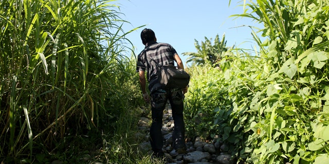 TALISMAN, MEXICO - AUGUST 01: An undodumented immigrant peers ahead after crossing the Suchiate River from Guatemala into Mexico on August 1, 2013 in Talisman, Mexico. Thousands of Central Americans pass illegally into Mexico daily, many of them immigrants on the first leg of their long and perilous journey north towards the United States. (Photo by John Moore/Getty Images)
