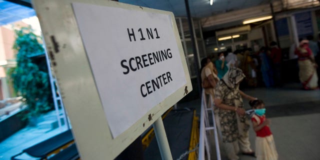 A mother helps her daughter wear a respiratory mask outside a H1N1 Swine flu examination center at a government hospital in New Delhi, India, Sunday, Aug. 9, 2009. Media reports say three more people infected with swine flu have died in India, raising the country's death toll related to the virus to four. (AP Photo/Mustafa Quraishi)