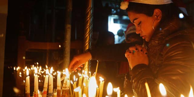 A Christian worshipper prays after lighting a candle on Christmas Eve at the Church of the Nativity, built atop the site where Christians believe Jesus Christ was born, in the West Bank City of Bethlehem, Saturday, Dec. 24, 2016.