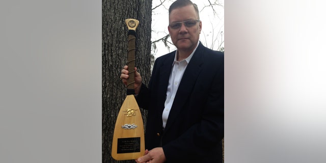 Navy Chaplain Wes Modder is pictured with a ceremonial oar presented to him by Naval Special Warfare Command. He received the oar at the end of his tour.