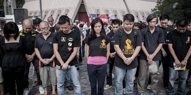 Around a dozen people wearing black clothes hold a minute's silence to mark the first anniversary of a fatal sea disaster which claimed 39 lives in Hong Kong on October 1, 2013