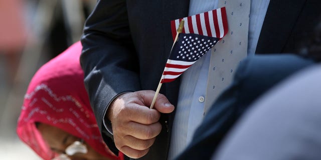 NEW YORK, NY - JULY 22: A man holds an American Flag before taking the Oath of Allegiance during a special naturalization ceremony at the Metropolitan Museum of Art on July 22, 2014 in New York City. Over fifty people representing countries from Albania to Burundi took part in the morning ceremony at the American Wing of the museum. The Oath of Allegiance was administered by U.S. Citizenship and Immigration Services (USCIS) Deputy Director Lori L. Scialabba. (Photo by Spencer Platt/Getty Images)