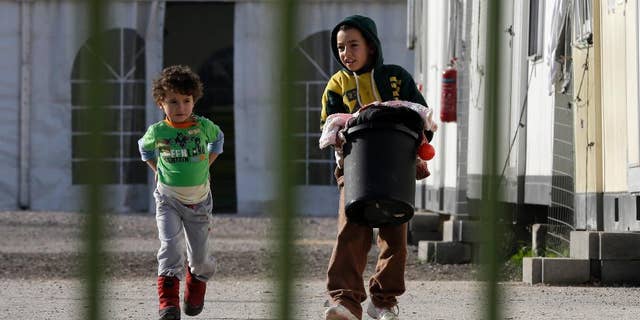 A boy carries a basket of laundry as another child follows him inside Eleonas refugee camp near central Athens Monday, Dec. 14, 2015. Financially stricken Greece is the main entry point for asylum-seekers trying to enter the 28-nation European Union. More than 700,000 people have arrived so far this year but few want to remain in the country, with almost all heading to more prosperous European nations. (AP Photo/Thanassis Stavrakis)