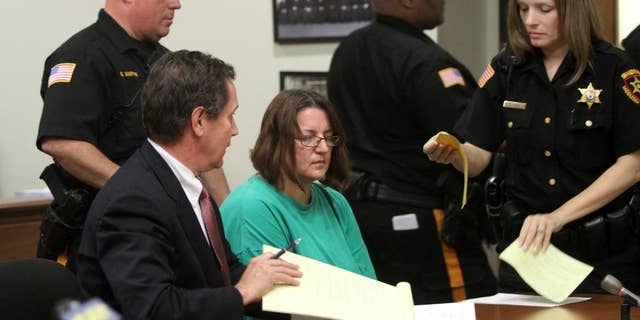FILE - In this Sept. 16, 2014 file photo, Michelle Lodzinski, center, sits beside her attorney Gerald Krovatin during her arraignment in New Jersey Superior Court in New Brunswick, N.J. Lodzinski, a resident of Port St. Lucie, Fla., was convicted on Wednesday, May 18, 2016, of killing her 5-year-old son Timothy Wiltsey in New Jersey in May 1991. (Jason Towlen/Home News Tribune via AP, Pool, File)