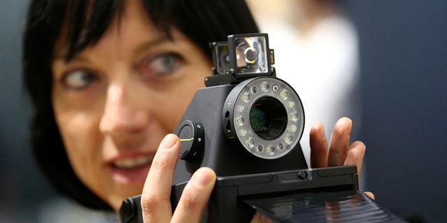 File photo: A woman takes a picture with the Impossible I-1 analog instant camera, the first new camera system working with the original Polaroid photo format, at the booth of the Impossible project on the Photokina, the world's largest fair for imaging in Cologne, Germany, September 20, 2016. (REUTERS/Fabrizio Bensch)