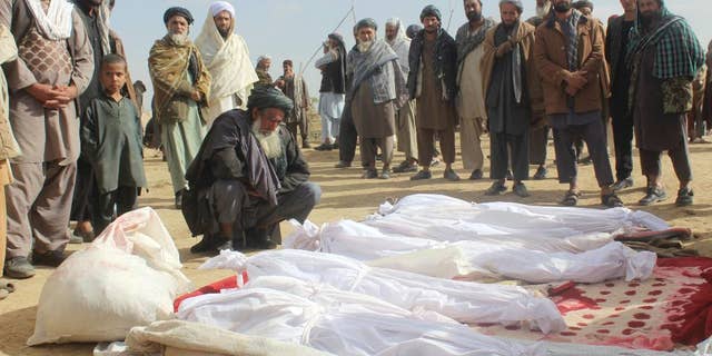 FILE -- In this Nov. 4, 2016 file photo, Afghan villagers gather around several victims' bodies who were killed during clashes between Taliban and Afghan security forces in the Taliban-controlled, Buz-e Kandahari village in Kunduz province, Afghanistan. In a statement released Thursday, Jan. 12, 2017, the U.S. military in Afghanistan said the results of its investigation into the November firefight with the Taliban in Kunduz province show that American troops had fired on Afghan homes, killing 33 civilians. (AP Photo/Najim Rahim, File)