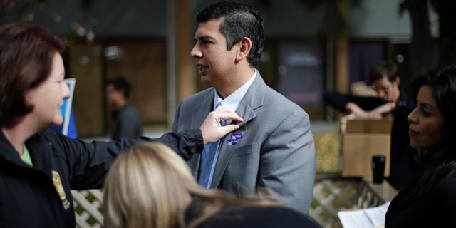 David Alvarez, center, a San Diego city councilman and Democratic candidate for mayor, stands while California Assembly Majority Leader Toni Atkins, left, adjusts a pin on his lapel as he meets with supporters Tuesday, Nov. 19, 2013, in San Diego. San Diegans head to the polls today to choose a new mayor, after Bob Filner's resignation amid allegations of sexual harassment has left the city with an interim mayor. (AP Photo/Gregory Bull)