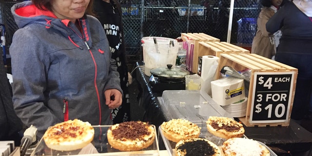 Vendors at the Queens Night Market in New York City's Corona, Queens, neighborhood, selling Indonesian coconut cake snacks with various toppings. 
