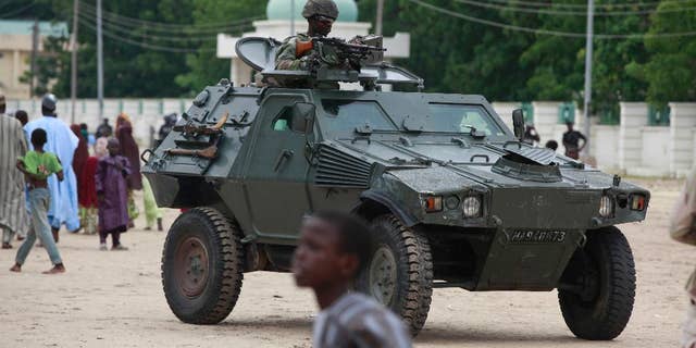 FILE - In this Thursday, Aug. 8, 2013 file photo, Nigerian soldiers ride on an armored personnel carrier during Eid al-Fitr celebrations in Maiduguri, Nigeria. Hundreds of Boko Haram extremists tried to attack the biggest army base in northeast Nigeria overnight but met fierce resistance from soldiers who fired artillery throughout the night. Booming cannon and whooshing rockets woke people living around Giwa Barracks in Maiduguri, the northeast's biggest city. Hundreds fled though some were returning home Thursday, May 14, 2015. Many villagers were killed by shells that hit the outlying village of Kayamla, where the soldiers engaged hundreds of militants, according to Muhammad Gava, a hunter who is secretary of the self-defense Vigilante Group of Nigeria. (AP Photo/Sunday Alamba, File)