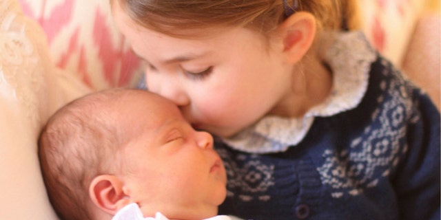 In this May 2, 2018 photograph provided by Kensington Palace, Britain's Princess Charlotte cuddles her brother Prince Louis, on her third birthday, at Kensington Palace, in London.